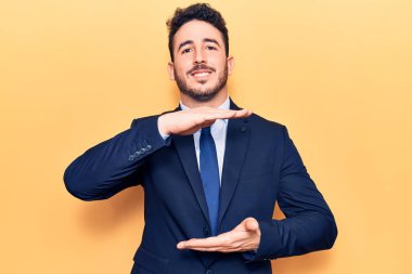 Elleriyle işaret eden, büyük ve büyük bir işaret gösteren, takım elbiseli İspanyol bir adam. Kameraya bakıp gülümsüyor. ölçüm kavramı. 