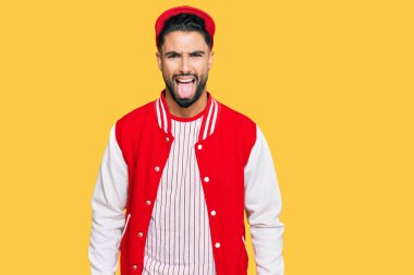 Beyzbol üniforması giyen sakallı genç adam komik bir ifadeyle dilini dışarı çıkarıyor. duygu kavramı. 