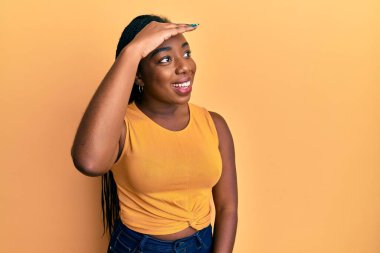 Genç Afro-Amerikan kadın günlük giysiler giyiyor çok mutlu ve gülümsüyor başlarını kaldırıp uzaklara bakıyor. arama kavramı. 