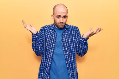 Genç, yakışıklı, kel, sıradan bir gömlek giyen, kafası karışık, kolları açık, hiçbir fikri olmayan, şüpheli bir yüzü olan bir adam.. 