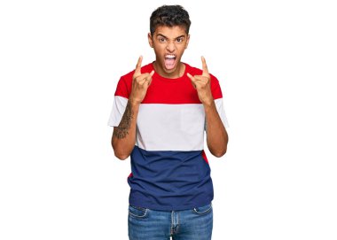 Genç, yakışıklı, Afro-Amerikalı, günlük kıyafetler giymiş, çılgın bir ifadeyle bağırıyor, elleri havada rock sembolü yapıyor. Müzik yıldızı. ağır kavram. 