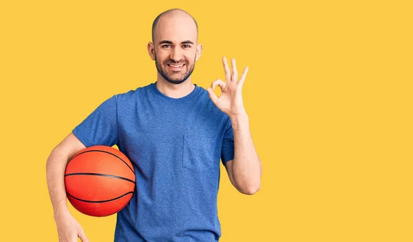 年轻英俊的男子手握篮球 手握手签 微笑友善的手势 是极好的象征 — 图库照片