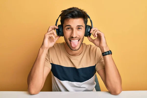 Νεαρός Όμορφος Άντρας Ακούει Μουσική Φορώντας Ακουστικά Βγάζοντας Γλώσσα Χαρούμενος — Φωτογραφία Αρχείου