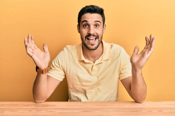 Joven Hombre Hispano Con Ropa Casual Sentado Mesa Celebrando Loco — Foto de Stock