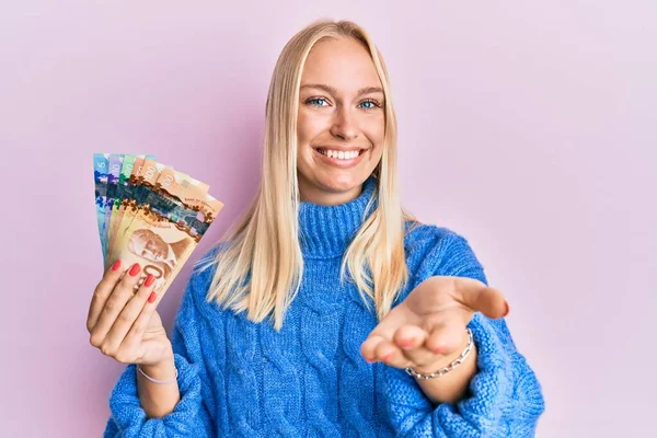 Young Blonde Girl Holding Canadian Dollars Smiling Cheerful Offering Palm — Stock Photo, Image