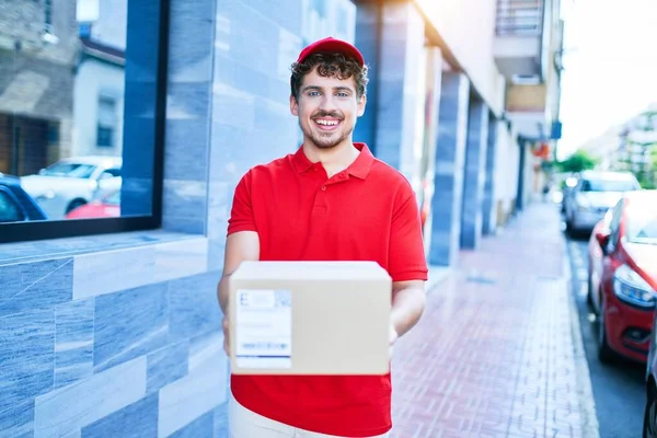 Jovem Homem Entrega Caucasiano Sorrindo Feliz Segurando Pacote Papelão Andando — Fotografia de Stock