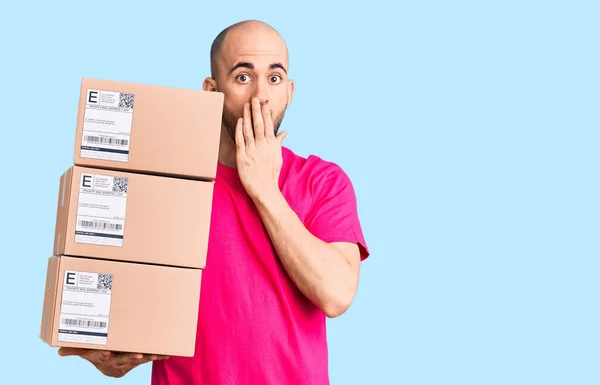 Young Handsome Man Holding Delivery Package Covering Mouth Hand Shocked — Stock Photo, Image