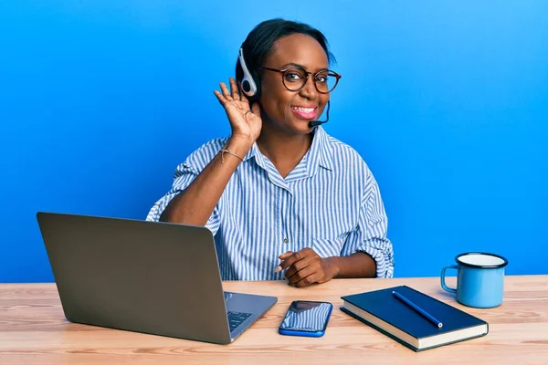 コールセンターエージェントのヘッドセットを身に着けている若いアフリカの女性は 耳を傾け 噂やゴシップに耳を傾け笑顔 聴覚障害の概念 — ストック写真