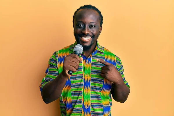 Guapo Joven Negro Cantando Canción Usando Micrófono Sonriendo Feliz Señalando — Foto de Stock