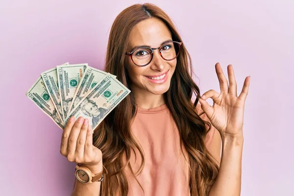Jovem Morena Segurando Dólares Fazendo Assinar Com Dedos Sorrindo Simpática — Fotografia de Stock