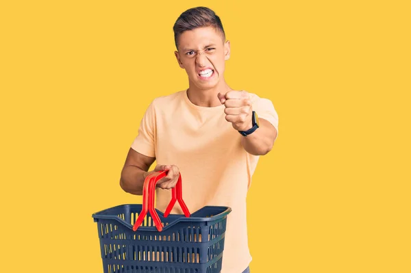 Młody Przystojny Latynos Trzymający Koszyk Zakupów Supermarkecie Zirytowany Sfrustrowany Krzykiem — Zdjęcie stockowe