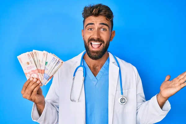 Joven Hispano Vistiendo Uniforme Médico Sosteniendo Pesos Colombianos Celebrando Logro — Foto de Stock