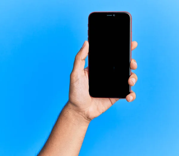 Hand Van Jonge Spaanse Man Toont Smartphone Geïsoleerde Blauwe Achtergrond — Stockfoto