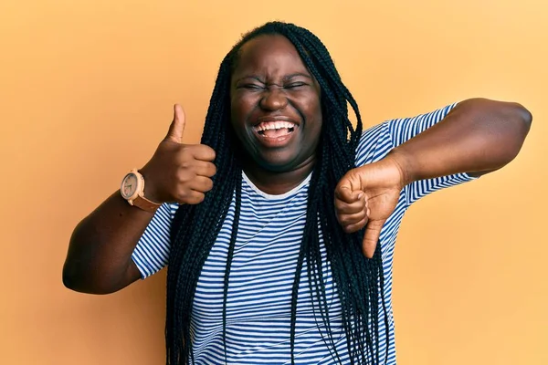 Örgülü genç siyahi kadın baş parmağını kaldırıyor ve baş parmağını kaldırıyor. Gülümsüyor ve kahkahalarla gülüyor. Çünkü komik, çılgınca bir şaka.. 