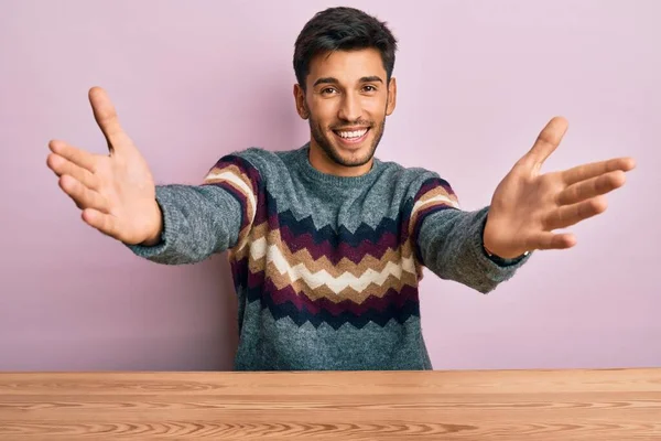 스웨터를 테이블에 포옹을 벌리고 잘생긴 청년이다 행복을 포용하는 — 스톡 사진