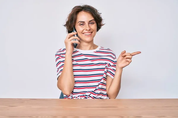 Jonge Spaanse Vrouw Praten Smartphone Zitten Tafel Glimlachend Gelukkig Wijzend — Stockfoto