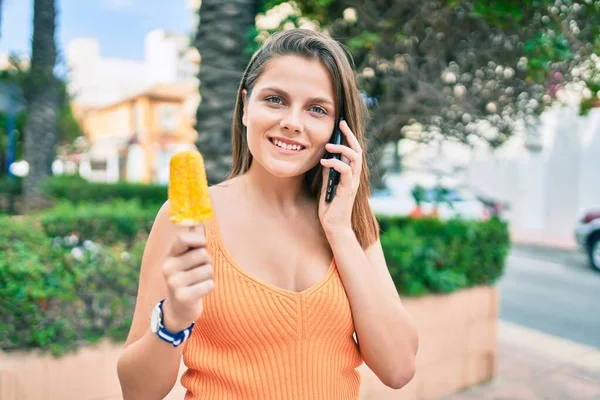 若いです中東の女の子話していますザスマートフォン食べてアイスクリームで街 — ストック写真