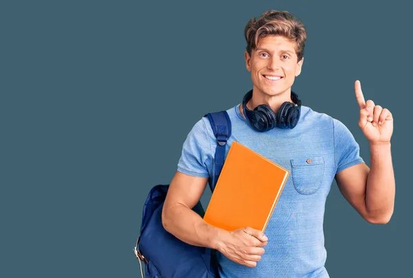 Junger Gutaussehender Mann Mit Studentenrucksack Und Kopfhörer Buch Der Hand — Stockfoto