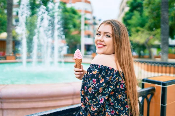 若いです赤毛女性笑顔幸せな食べるアイスクリーム傾きオンザBalustrade — ストック写真