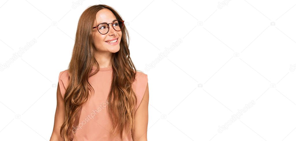 Young hispanic woman wearing casual clothes and glasses looking away to side with smile on face, natural expression. laughing confident. 
