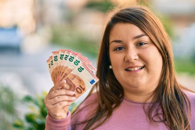 Genç İspanyol artı iri kadın gülümseyerek şehirde 10 avroluk banknotlar tutuyor..