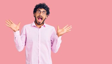 Kıvırcık saçlı ve ayı gibi giyinmiş yakışıklı genç adam çılgın iş kıyafetleri giyiyor ve kollarını kaldırıp heyecanla haykırarak başarıyı kutluyor. Kazanan konsept 