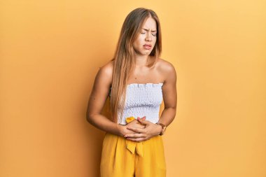 Güzel, genç, sarışın bir kadın gündelik kıyafetlerini giyer, elleri karnında, çünkü hazımsızlık, acı verici bir hastalık, kendini iyi hissetmiyor. Ağrı kavramı. 