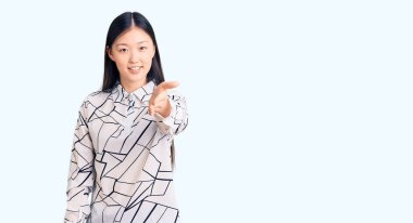 Genç, güzel, Çinli bir kadın, günlük tişört giyiyor, gülümsüyor, avuç içi kadar yardım ve kabul görüyor.. 