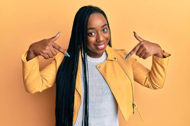 Genç Afro-Amerikan kadın rahat bir ceket giyiyor. Kendine güveni tam görünüyor. Kendini gururlu ve mutlu bir şekilde gösteriyor.. 