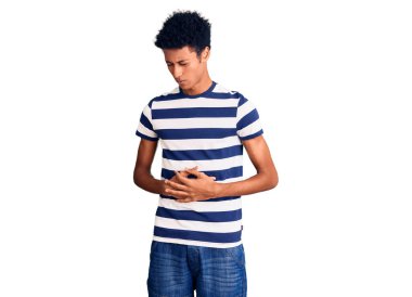 Afro-Amerikalı genç bir adam, hazımsızlık, acı verici bir hastalık ve midesi üzerine gündelik giysiler giyiyor. Ağrı kavramı. 