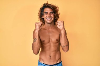 Kolları havada, gözleri kapalı zaferi kutlarken gülümseyen Latin asıllı genç adam başarı için heyecanla bekliyor. Kazanan konsept. 