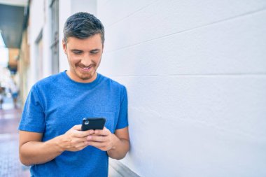 Beyaz adam şehirde akıllı telefon kullanarak mutlu bir şekilde gülümsüyor..