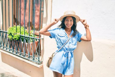 Genç, güzel Hintli bir kadın duvara yaslanıyor ve gülümsüyor..