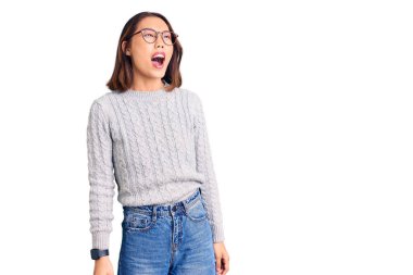 Genç, güzel Çinli bir kız, günlük kıyafetler giyiyor kızgın ve kızgın bağırıyor, sinirlenmiş ve öfkeli, öfkeyle bağırıyor. öfke ve agresif konsept. 