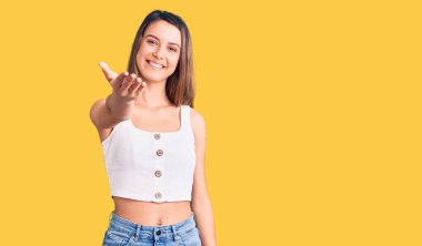 Kolsuz tişört giyen genç ve güzel bir kız dostça gülümseyerek selamlama ve hoş geldin diyor. başarılı iş. 