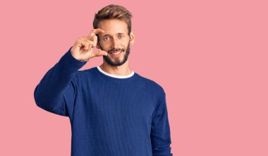 Sakallı yakışıklı, sıradan bir süveter giyen, gülümseyen, kendine güvenen, el hareketi yapan, parmaklarıyla işaret eden ve kameraya bakan bir adam. ölçüm kavramı. 