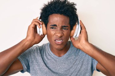 Afro saçlı, kulaklık takan ve kafası karışık bir ifadeyle müzik dinleyen yakışıklı Afro-Amerikan. şüphe kavramı. 