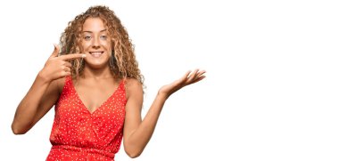 Yazlık elbise giyen güzel beyaz kız kameraya hayret ediyor ve gülümsüyor.. 