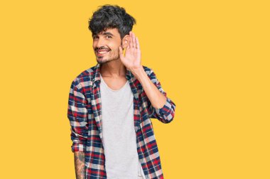 Gündelik kıyafetler giyen, ağzı kulaklarında gülümseyen genç İspanyol bir adam dedikoduları ve dedikoduları dinliyor. Sağırlık kavramı. 