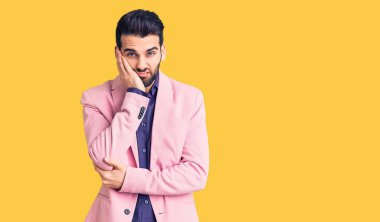 Sakallı, zarif ceketli genç ve yakışıklı bir adam kollarını kavuşturarak depresyondan sıkılmış ve yorgun görünüyor.. 