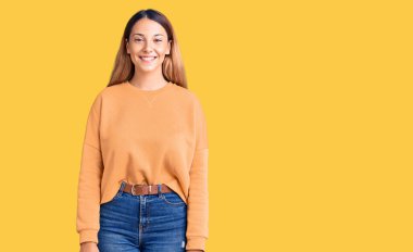 Yüzünde mutlu ve havalı bir gülümseme olan gündelik kıyafetler giyen güzel bir genç kadın. şanslı kişi. 