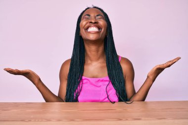 Saçları günlük kıyafetlerle örülü Afro-Amerikalı bir kadın masaya oturmuş başarıyı çılgınca ve çılgınca kutluyor kolları havada ve gözleri kapalı heyecanla bağırıyor. Kazanan konsept 