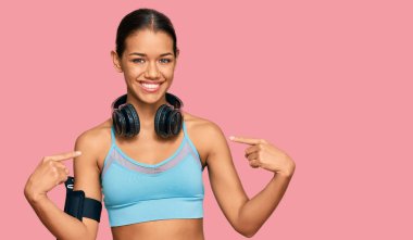 Spor giyim ve kulaklık takan, kendine güvenen, gülümseyen, kendini gururlu ve mutlu gösteren güzel İspanyol kadın.. 