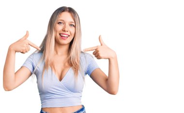 Genç, güzel, sarışın, gündelik kıyafetler giyen, kendine güvenen, gülümseyen, kendini gururlu ve mutlu gösteren bir kadın.. 