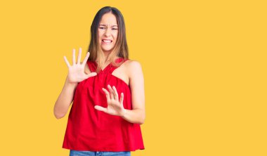 Güzel, esmer, sıradan kıyafetler giyen, tiksindirici ifadeler takınan, tiksindirici bakışlar atan, hoş olmayan genç bir kadın. Eller havada. 