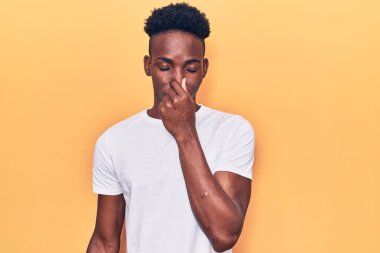 Genç, Afro-Amerikan bir adam günlük giysiler giymiş pis ve iğrenç bir koku alıyor, dayanılmaz bir koku, parmakları burnunda nefesini tutuyor. Kötü kokuyor. 