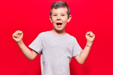 Hoş sarışın çocuk gündelik giysiler içinde gururla bağırıyor, zaferi kutluyor ve kollarını kaldırarak çok heyecanlanıyor. 