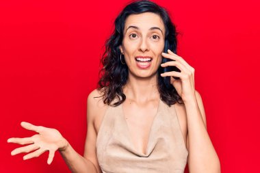 Genç ve güzel İspanyol bir kadın akıllı telefonda konuşuyor başarıyı mutlu bir gülümsemeyle kutluyor ve kazanan el kaldırarak ifade ediyor. 