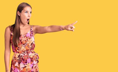 Genç ve güzel İspanyol elbiseli bir kadın parmağıyla işaret ediyor. İleride şaşırmış, ağzı açık, şaşırmış, ön tarafta bir şey var. 