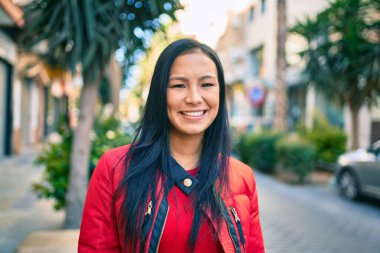 Genç Latin kadın gülümseyerek şehirde mutlu mesut yürüyor..